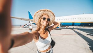 Ragazza felice scatta un selfie davanti a un aereo