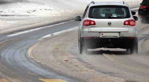 Auto si strada sporca di neve