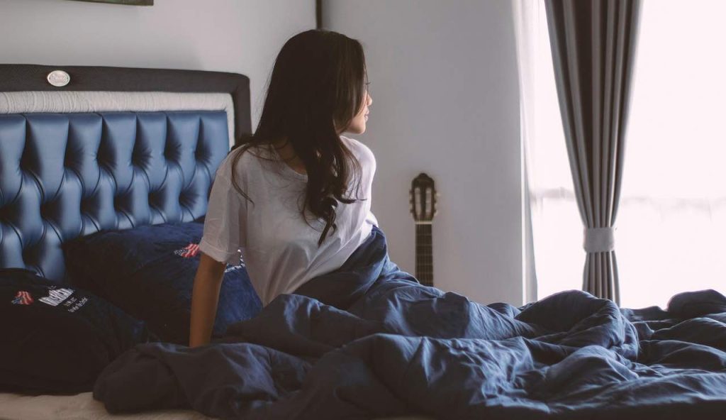 Donna sul letto che guarda dalla finestra